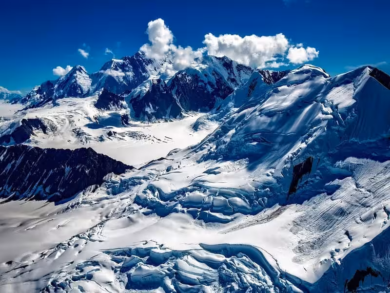 Expansive winter landscape in Alaska featuring snow-blanketed mountains and glaciers, illustrating why winter is a breathtaking time to visit.